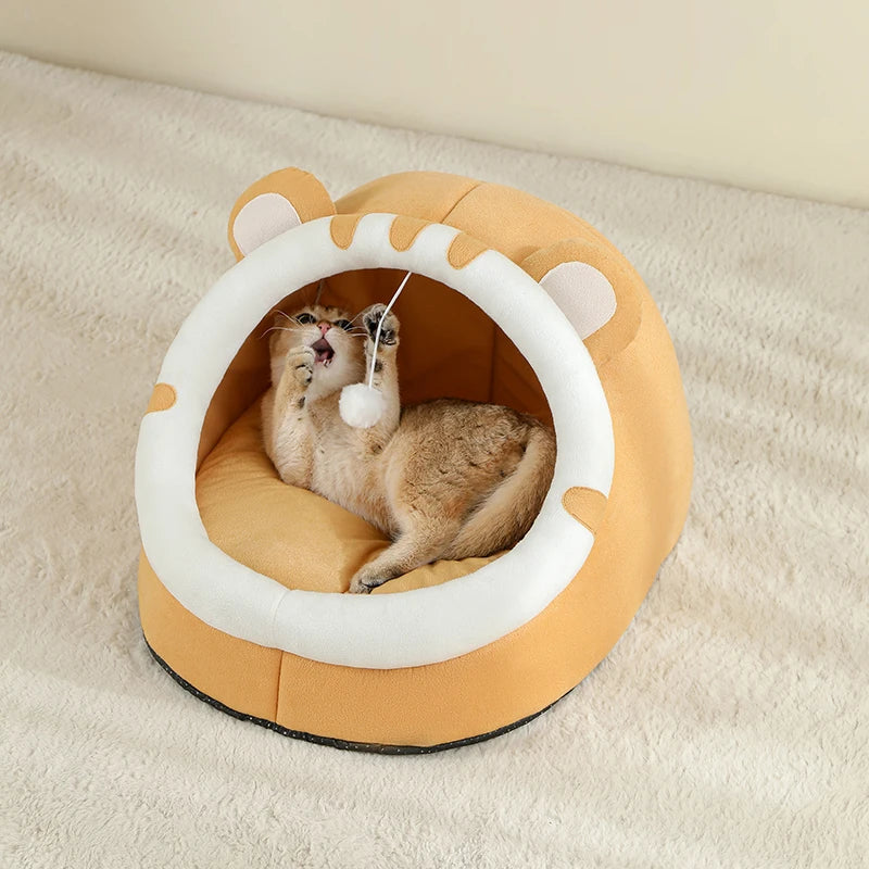 Cat playing with a toy inside a round, beige pet bed with white accents on a beige carpet.