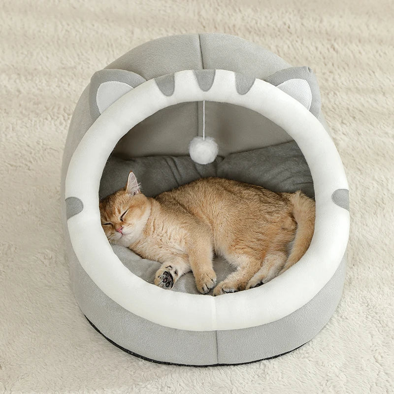 Cat sleeping in a gray pet bed with white interior on a beige carpet.

